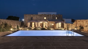 A poolside view of a building with a swimming pool, stone walls, and outdoor lighting. - Masseria Palane (Patu)