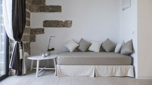 A modern living room with a sofa, a small round table, and a potted plant. - Masseria Palane (Patu)