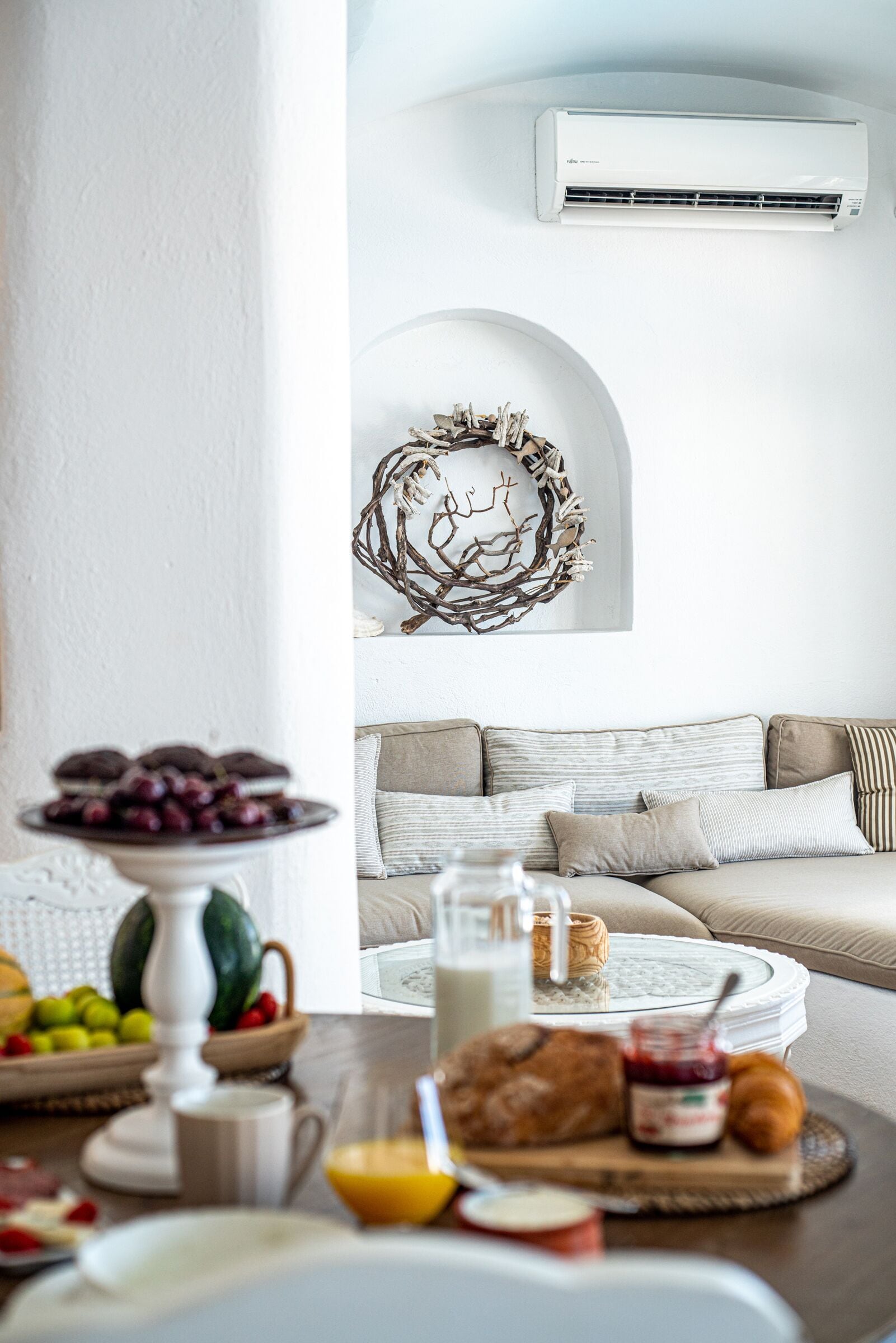A breakfast setup with a fruit bowl, croissants, and a coffee pot on a table.
