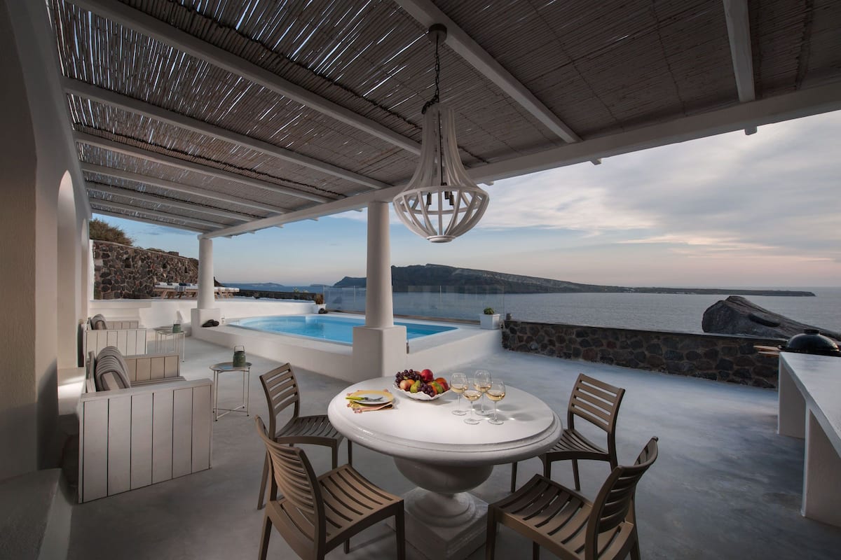 A modern outdoor dining area with a view of the sea and a pool.