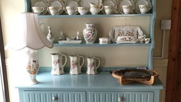 A light blue wooden cabinet with multiple shelves holding various white ceramic kitchenware items.
