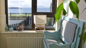 Een kamer met uitzicht op zee, een radiator, een lamp en een blauwe stoel.