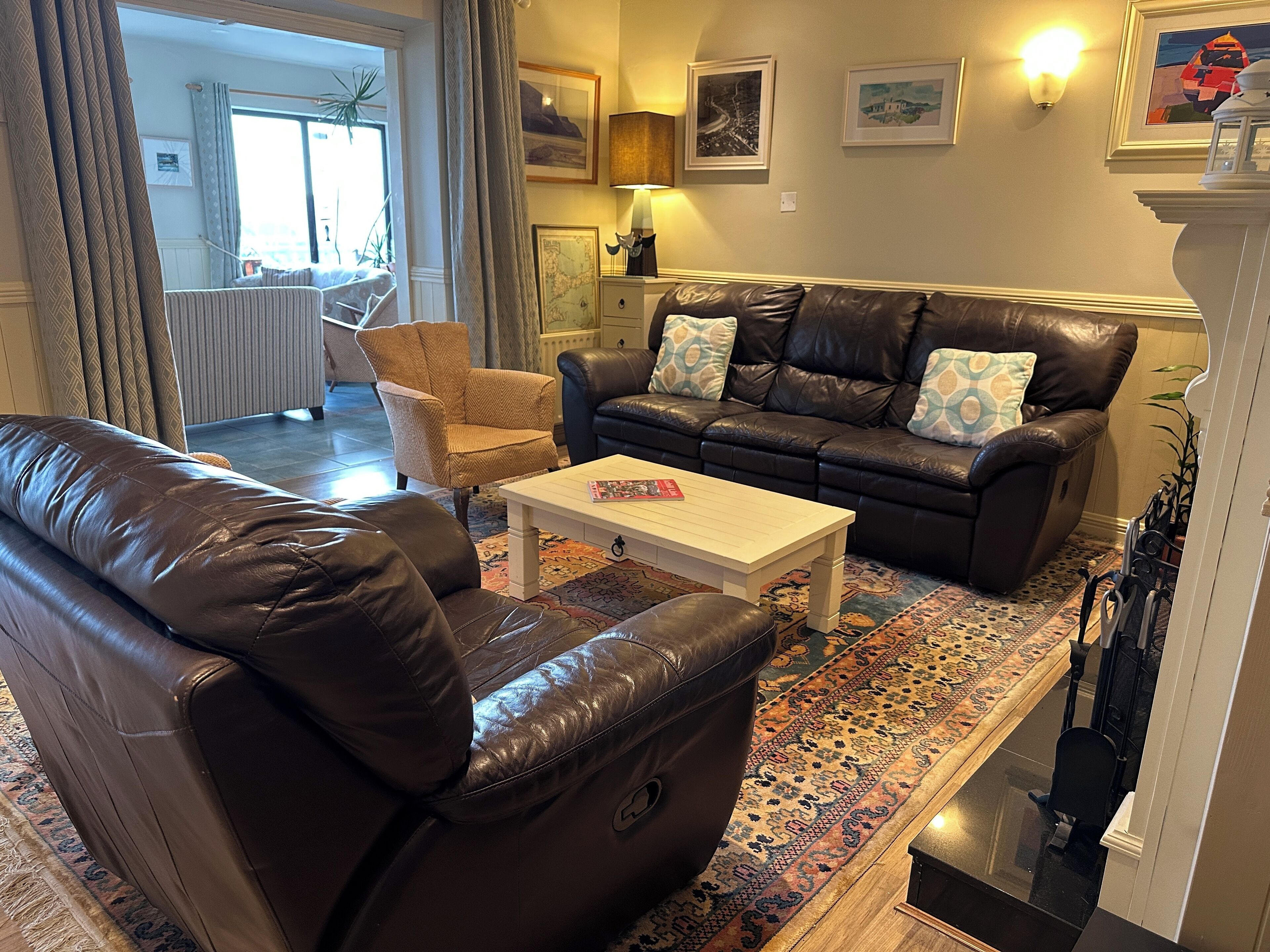 A living room with a brown leather sofa, a white coffee table, and a patterned rug.