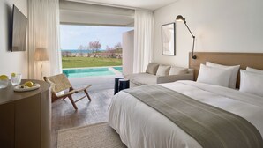 Habitación de hotel con una cama grande, un escritorio, una silla, una lámpara y vista al océano.