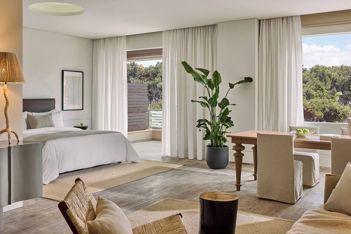A modern bedroom with a bed, a desk, and a potted plant.