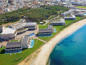 Un hotel costero con varias piscinas, una playa y un paisaje urbano de fondo.