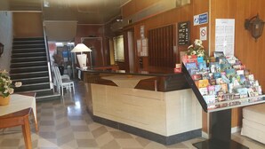 A reception area with a counter, a staircase, and a display of books and magazines. - Le Skippy (Saint-Pierre-des-Corps)