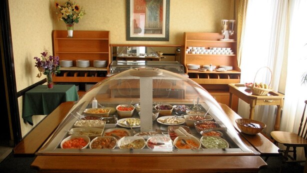 A buffet setup with various food items in glass containers, a coffee station, and a seating area with a table and chairs. - Le Skippy (Saint-Pierre-des-Corps)