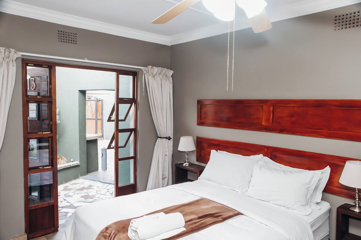 Una habitación de hotel con una cama grande, cabecera de madera y un ventilador de techo.