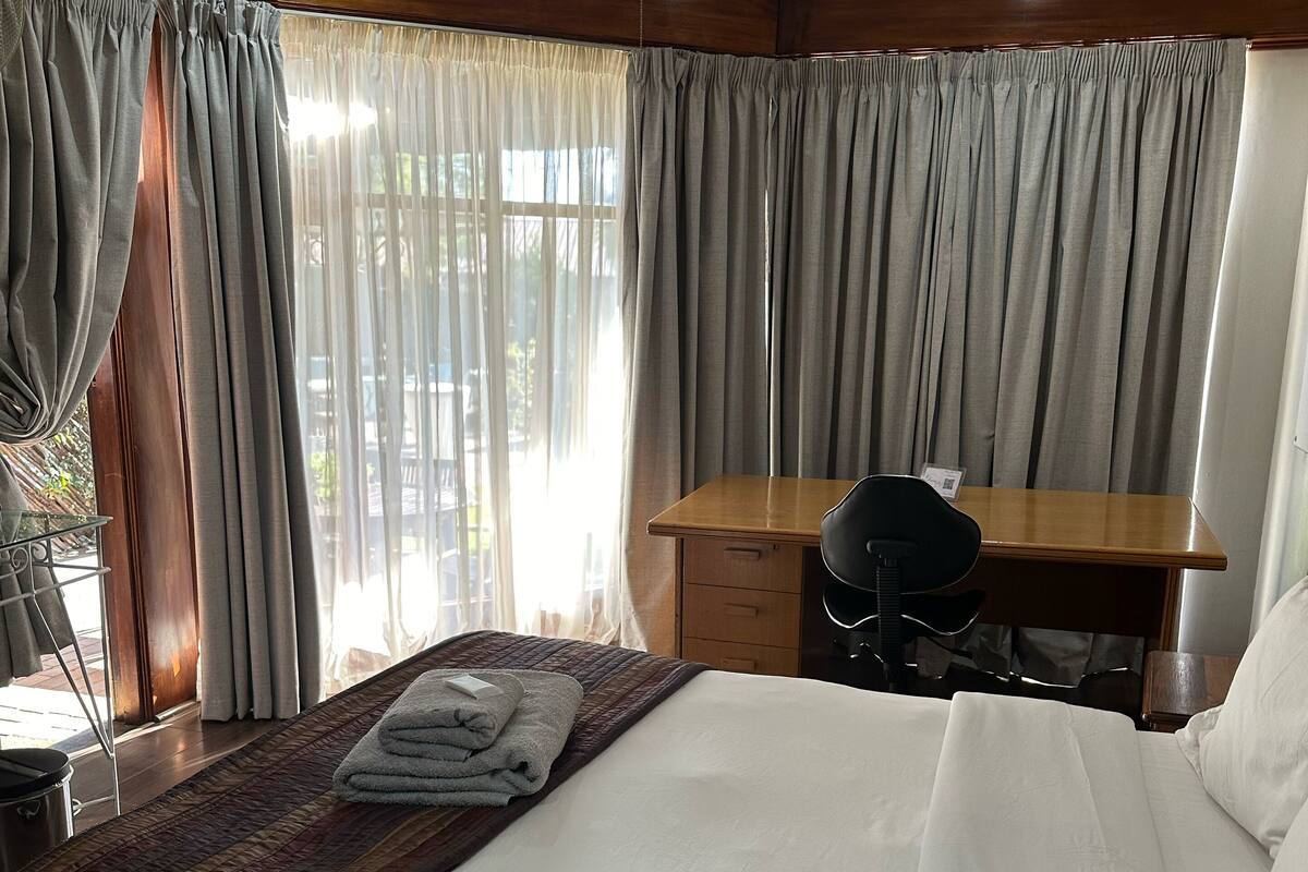 Una habitación de hotel con cama, escritorio y ventilador de techo.