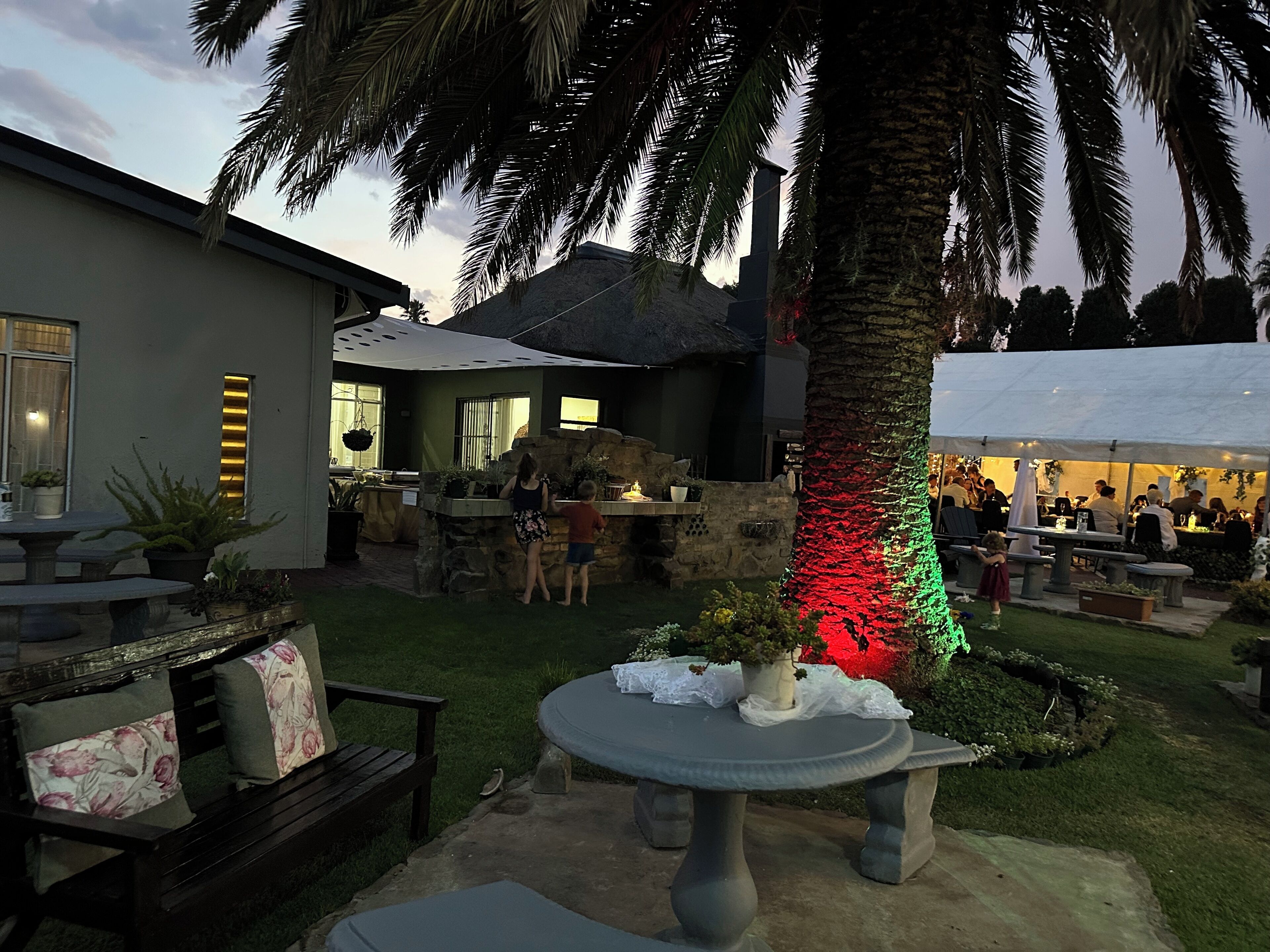 A patio area with a stone table, seating, a palm tree, and a stone wall.