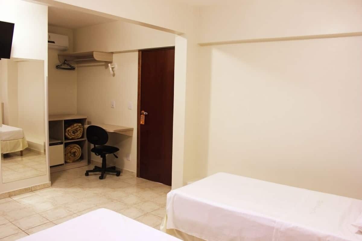 A bedroom with two beds, a desk, a chair, and a wardrobe.