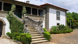 Un edificio histórico con una escalera de piedra que lleva a una zona cubierta con columnas.