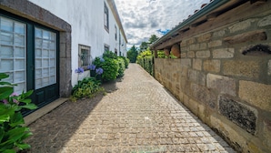 Un callejón empedrado flanqueado por edificios de paredes de piedra y un edificio blanco con puerta verde.