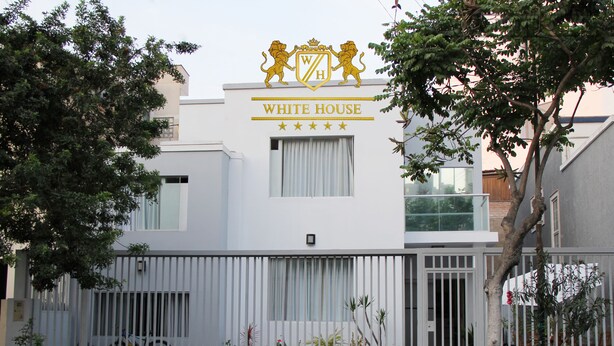 A building with a white facade, a crest with lions, and the name "WHITE HOUSE" above the entrance. - White House Peru (Lima)