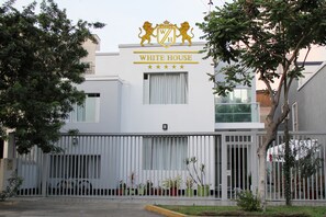A building with a white facade, a crest with lions, and the name "WHITE HOUSE" above the entrance. - White House Peru (Lima)