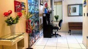 A reception area with a glass display case, a desk, a chair, a bench, and a vase with red flowers. - White House Peru (Lima)