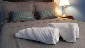 A neatly made bed with two pillows, a bedside lamp, and a folded towel on the bed. - White House Peru (Lima)