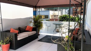 A balcony with a wicker sofa, a small table, and potted plants. - White House Peru (Lima)