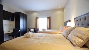 Habitación de hotel con dos camas, un escritorio, una silla y un televisor en la pared.