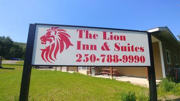 Une enseigne pour l’hôtel The Lion Inn & Suites, avec un logo représentant un lion et un numéro de téléphone.