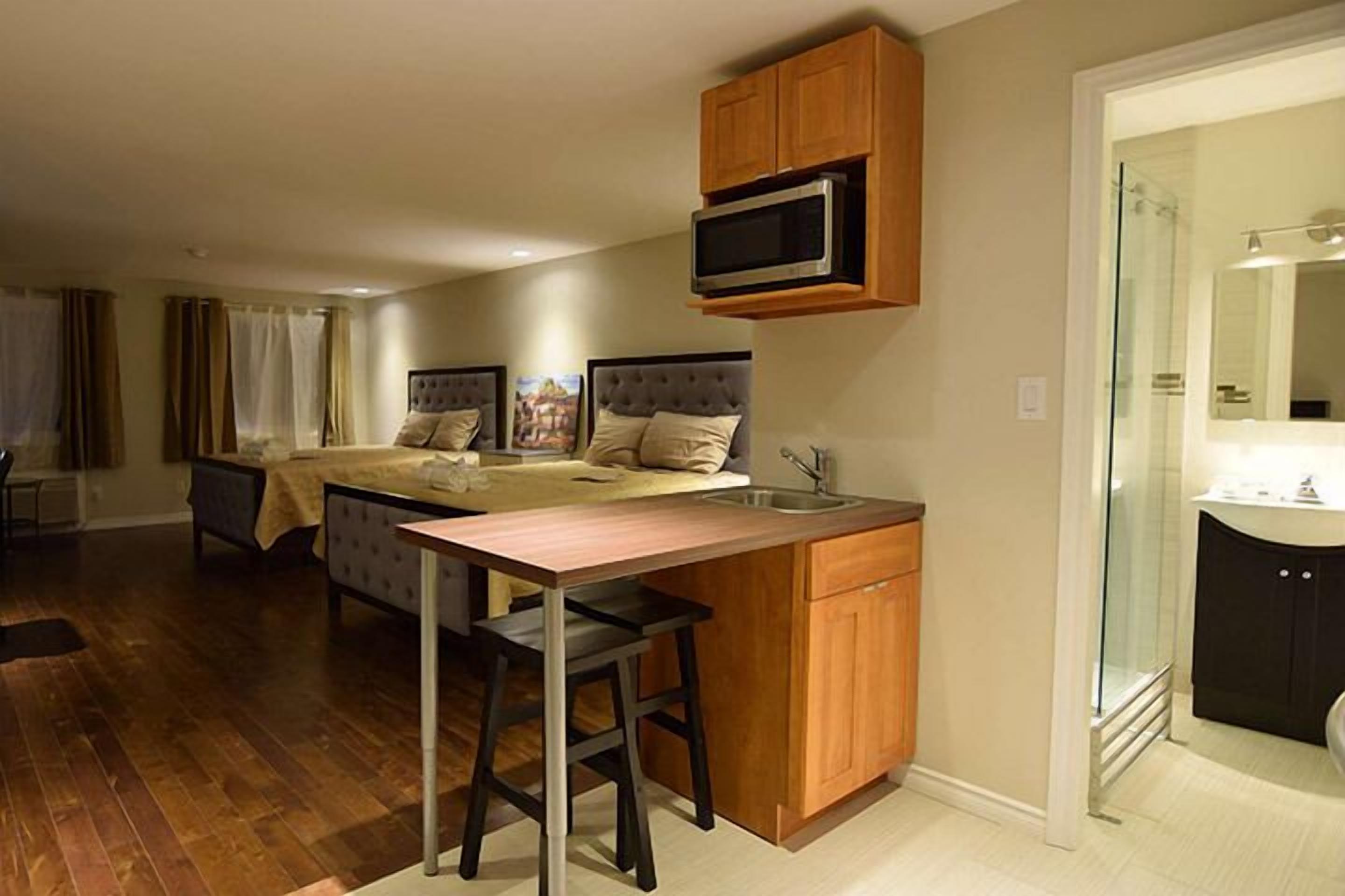 A compact room with a kitchenette, a bed, and a bathroom.