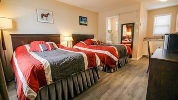 Habitación de hotel con dos camas, un escritorio y un espejo.