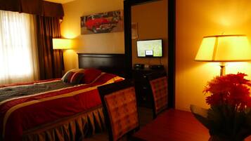 Ein Hotelzimmer mit Bett, Schreibtisch, Stuhl, Fernseher und Lampe.