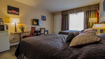 Una habitación de hotel con una cama grande, un escritorio con lámpara, televisión y ventana con cortinas.