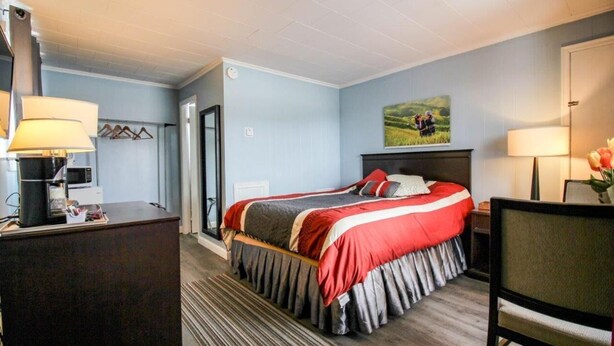 A hotel room with a bed, desk, and chair. - The White Horse Motel (Cornwall)