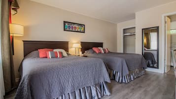 A hotel room with two beds, a mirror, a wardrobe, and a framed picture on the wall.