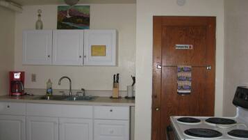 A kitchen with white cabinets, a coffee maker, a sink, and a stove.
