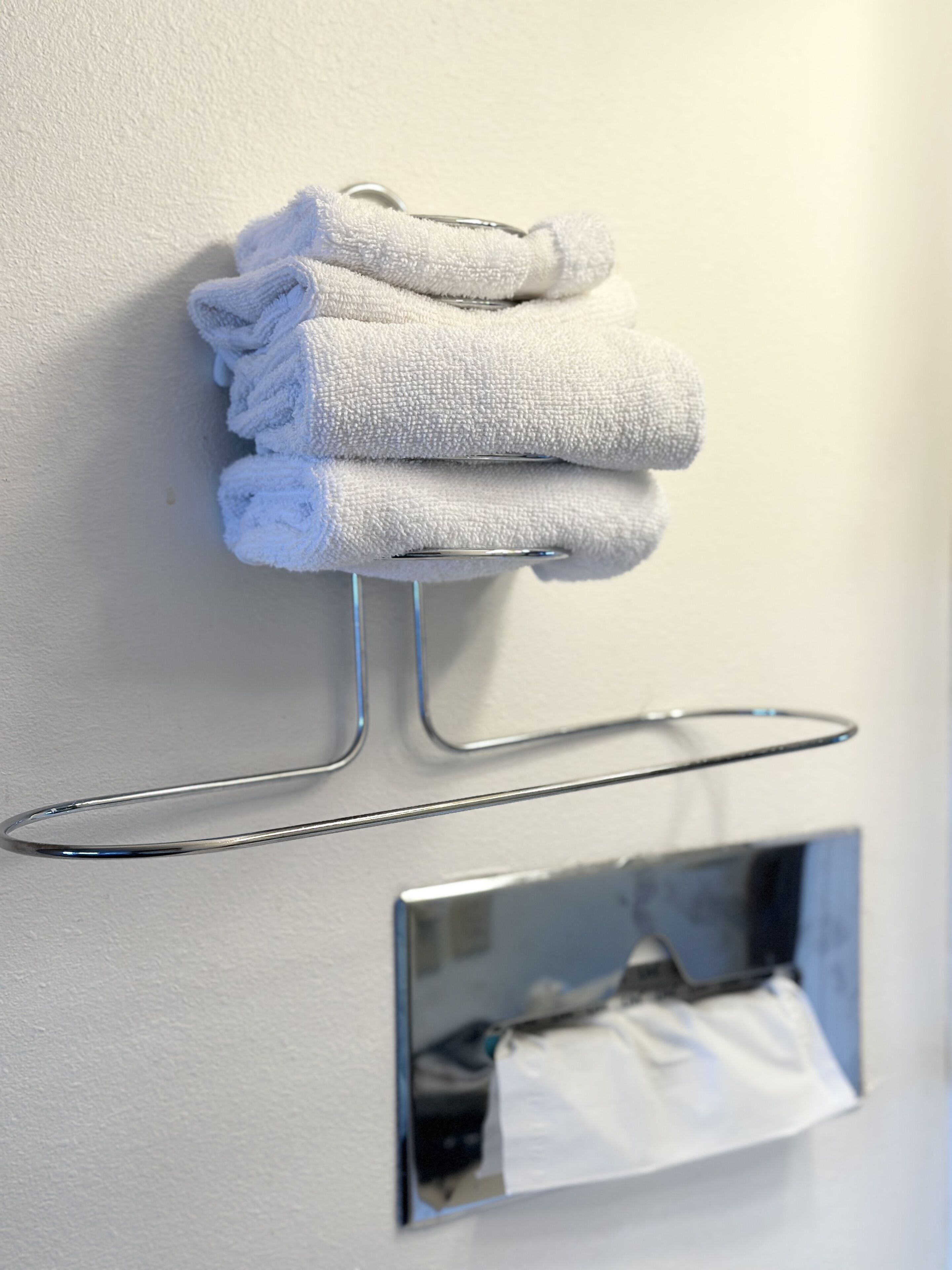 A wall-mounted towel rack with folded towels.