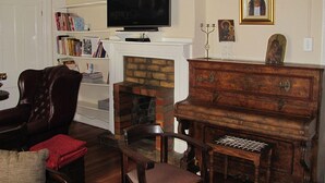 Un salon avec une cheminée, un téléviseur, une bibliothèque et un meuble en bois.
