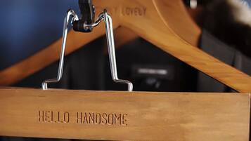 A wooden hanger with the text "HELLO HANDSOME" hanging on a metal rack.