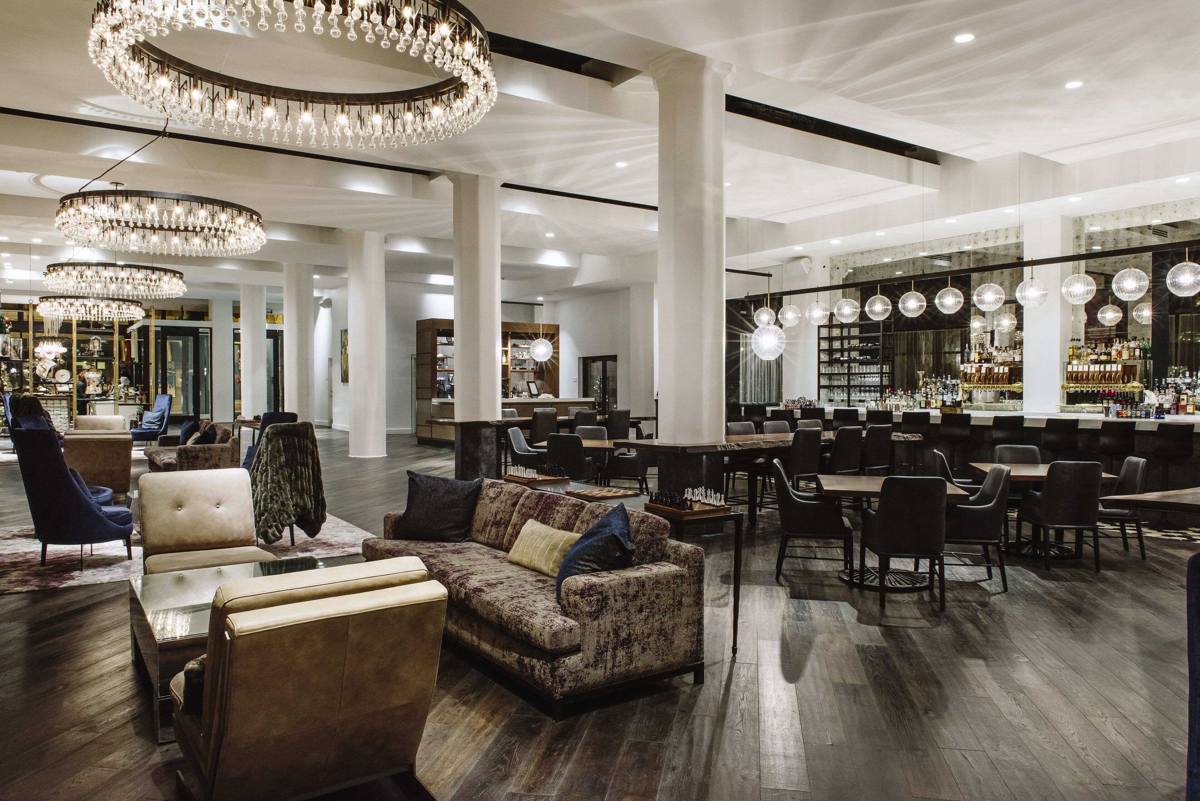 A spacious lobby with a bar area, seating arrangements, and a chandelier.