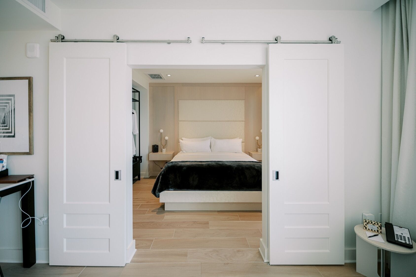 A modern bedroom with a large bed, a sliding door closet, and a bedside table with a lamp.
