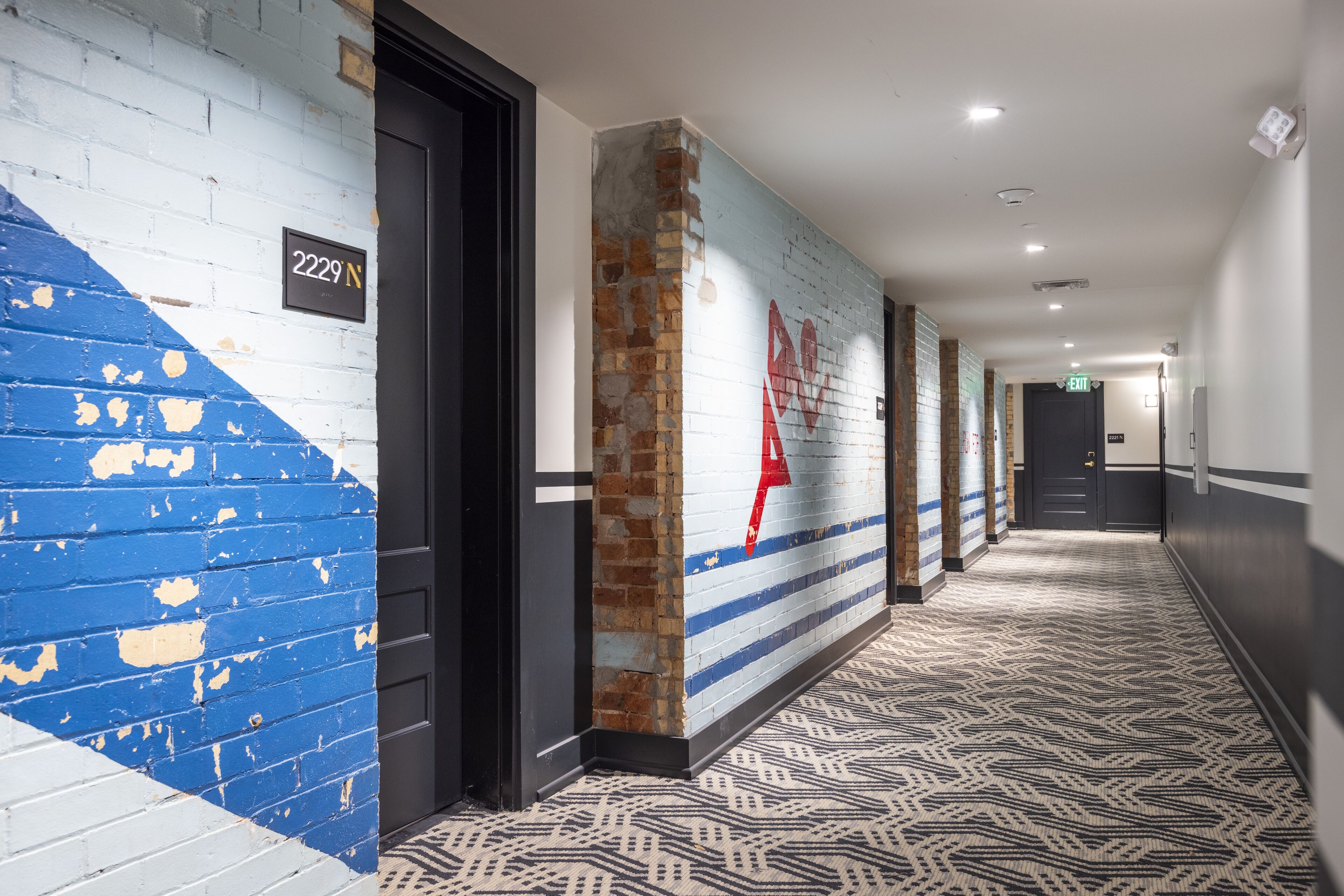 A hallway with a blue and white brick wall, a red heart decoration, and a patterned carpet.