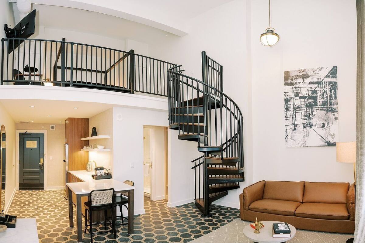 A spacious living area with a spiral staircase, a dining area, and a cozy seating area.