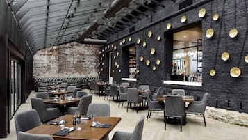 A restaurant with a brick wall, round gold accents, and modern seating.