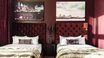 A hotel room with two beds, a nightstand, and two wall-mounted paintings.