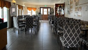 A restaurant with patterned booths and tables, a menu on the wall, and a sign indicating the restroom direction. - Kluane Park Inn (Haines Junction)