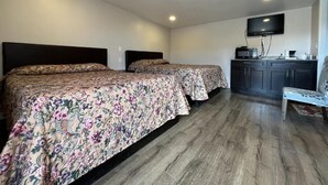 A room with two beds, a flat-screen TV, a microwave, and a small table. - Kluane Park Inn (Haines Junction)