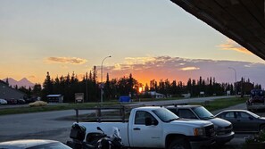A parking area with vehicles, a business section sign, and a mountain in the background. - Kluane Park Inn (Haines Junction)