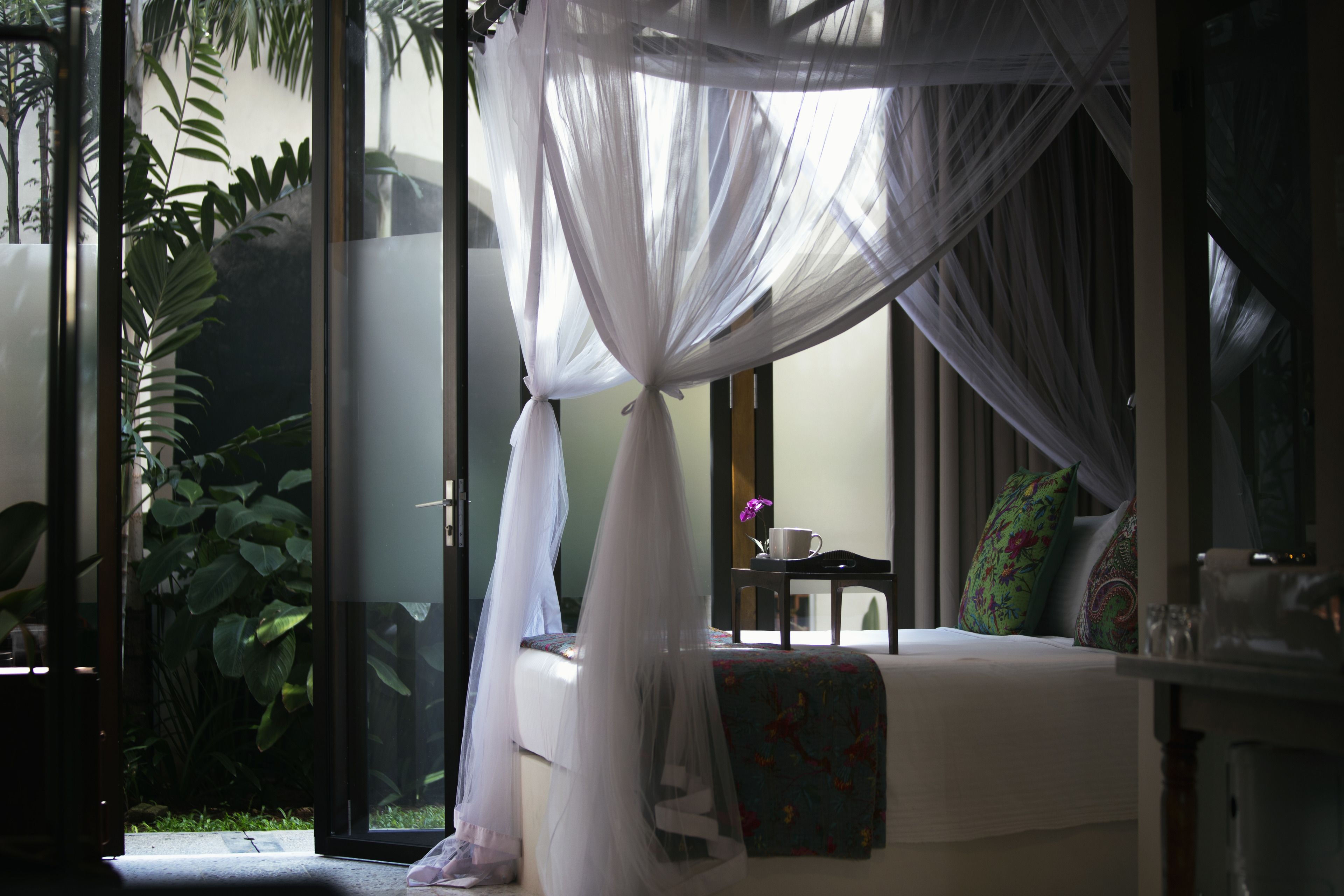 Una habitación con cama, una mesita y una ventana con vistas al verdor.