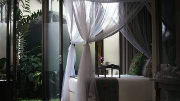 Una habitación con cama, una mesita y una ventana con vistas al verdor.