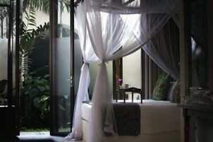 Una habitación con cama, una mesita y una ventana con vistas al verdor.