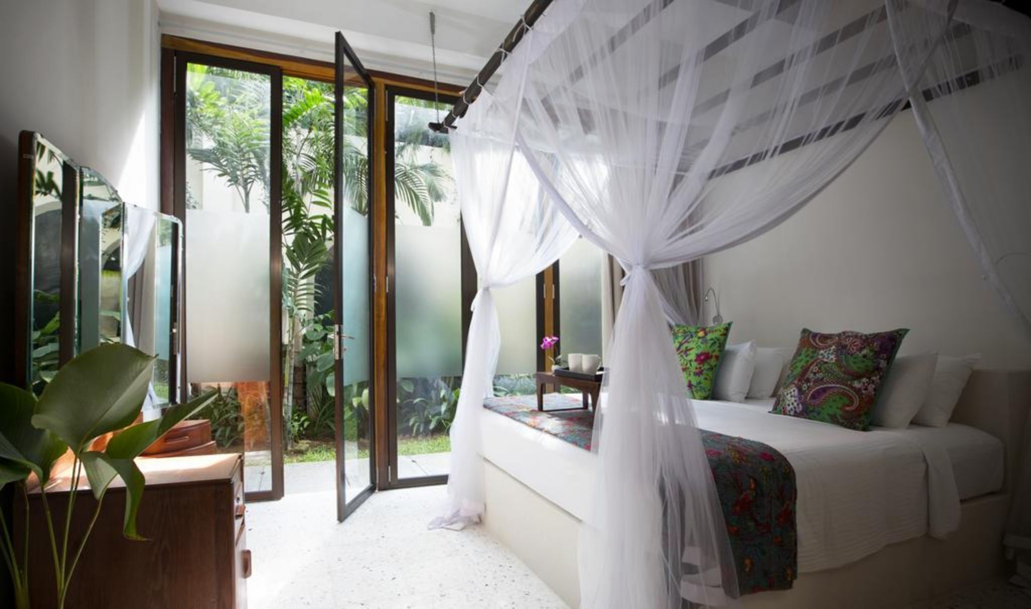 A bedroom with a bed, a window, and a view of greenery.