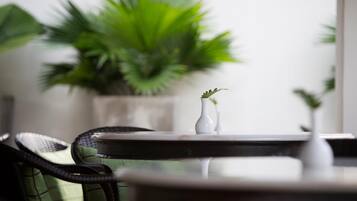 A round table with a white vase and a green plant in the background.