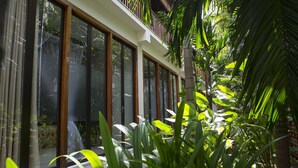 Un bâtiment moderne doté de grandes fenêtres en verre et d’un balcon donnant sur une végétation luxuriante.